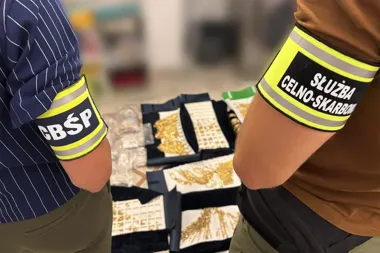Funkcjonariusze CBŚP i Służby Celno-Skarbowej stoją przy stole z zarekwirowaną biżuterią i przedmiotami ze złota.